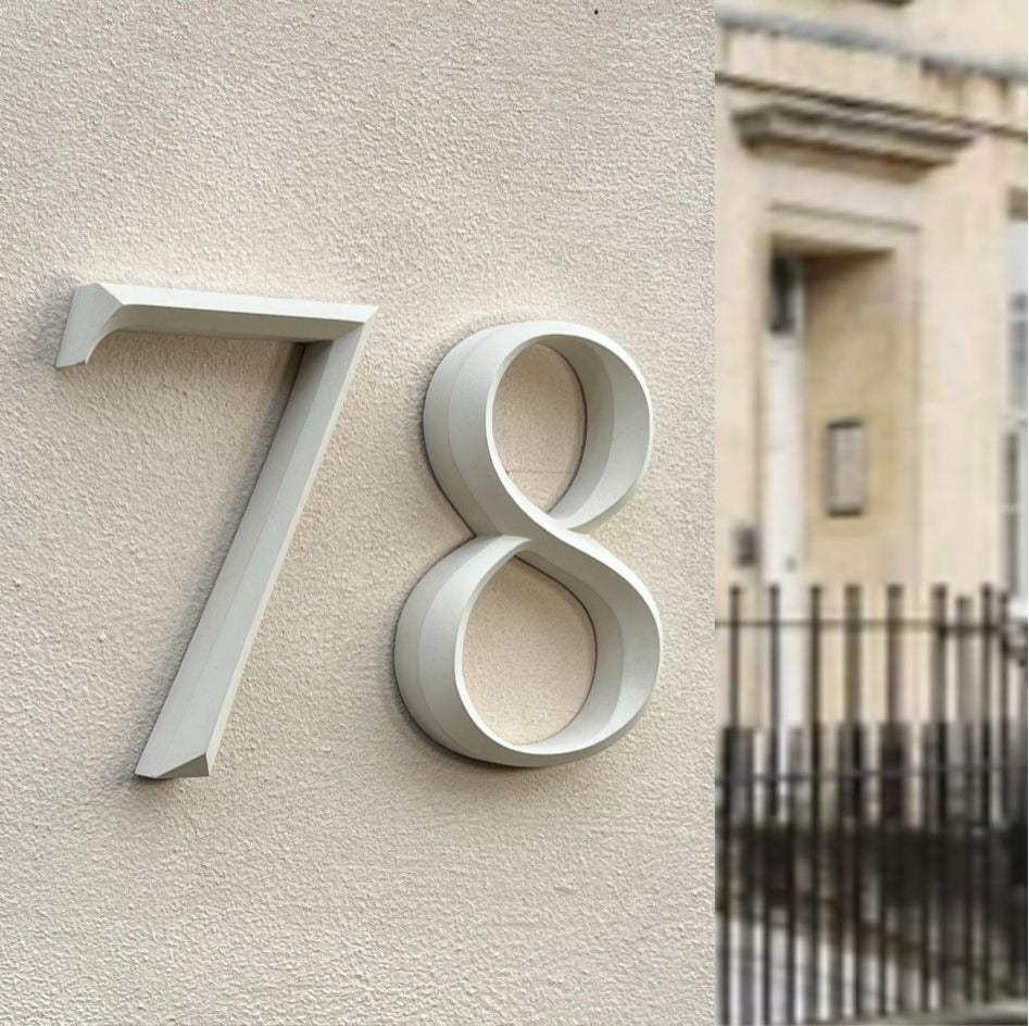 Floating cast stone house number '78' elegantly mounted on a textured wall. Featuring a prismatic serif design, the luxury house sign enhances modern and classical homes with a timeless architectural appeal.